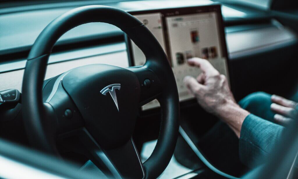 Tesla Auto von innen mit Hand, die das Touchdisplay bedient