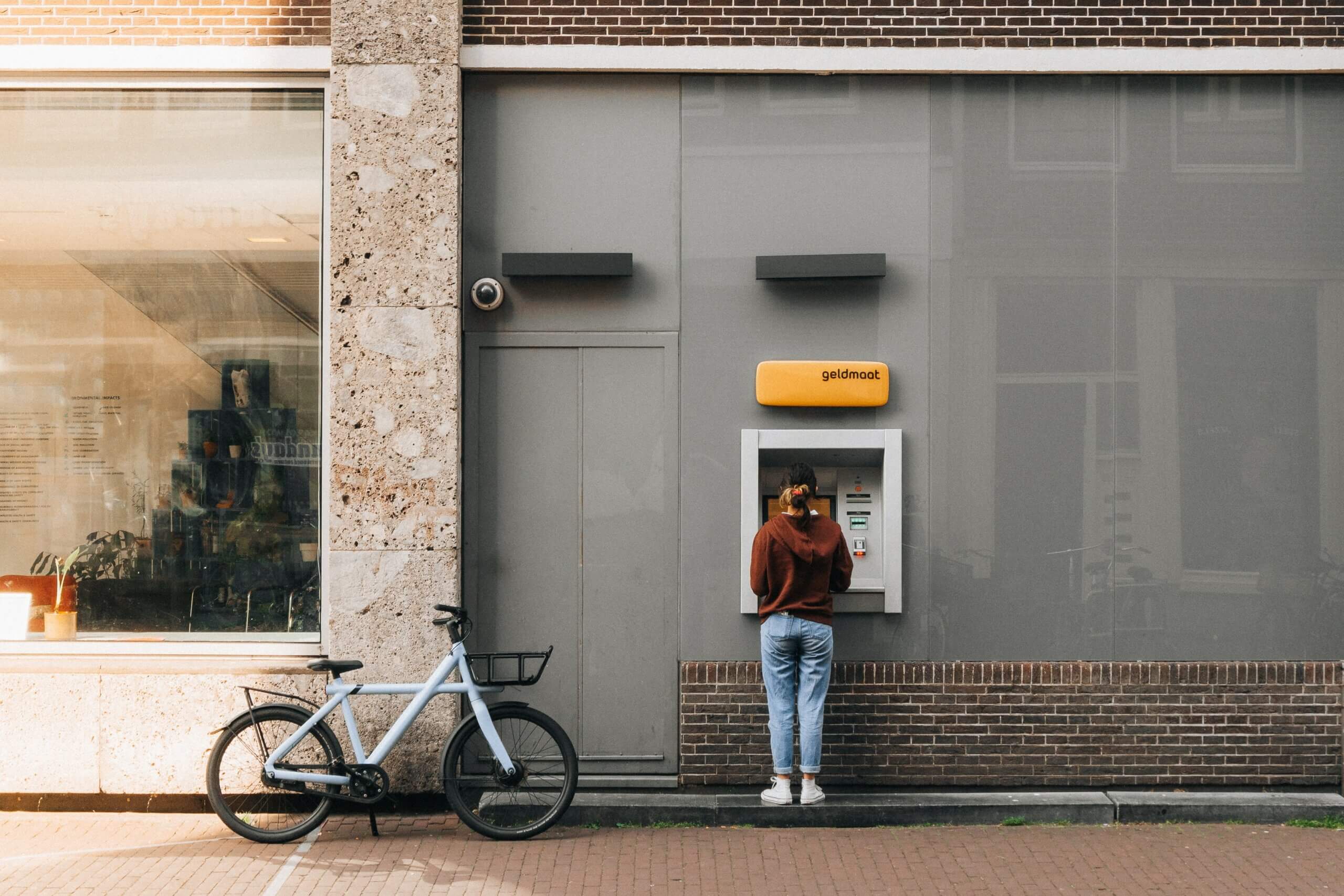 VanMoof E-Bike steht neben Person an einem Geldautomaten in Amsterdam