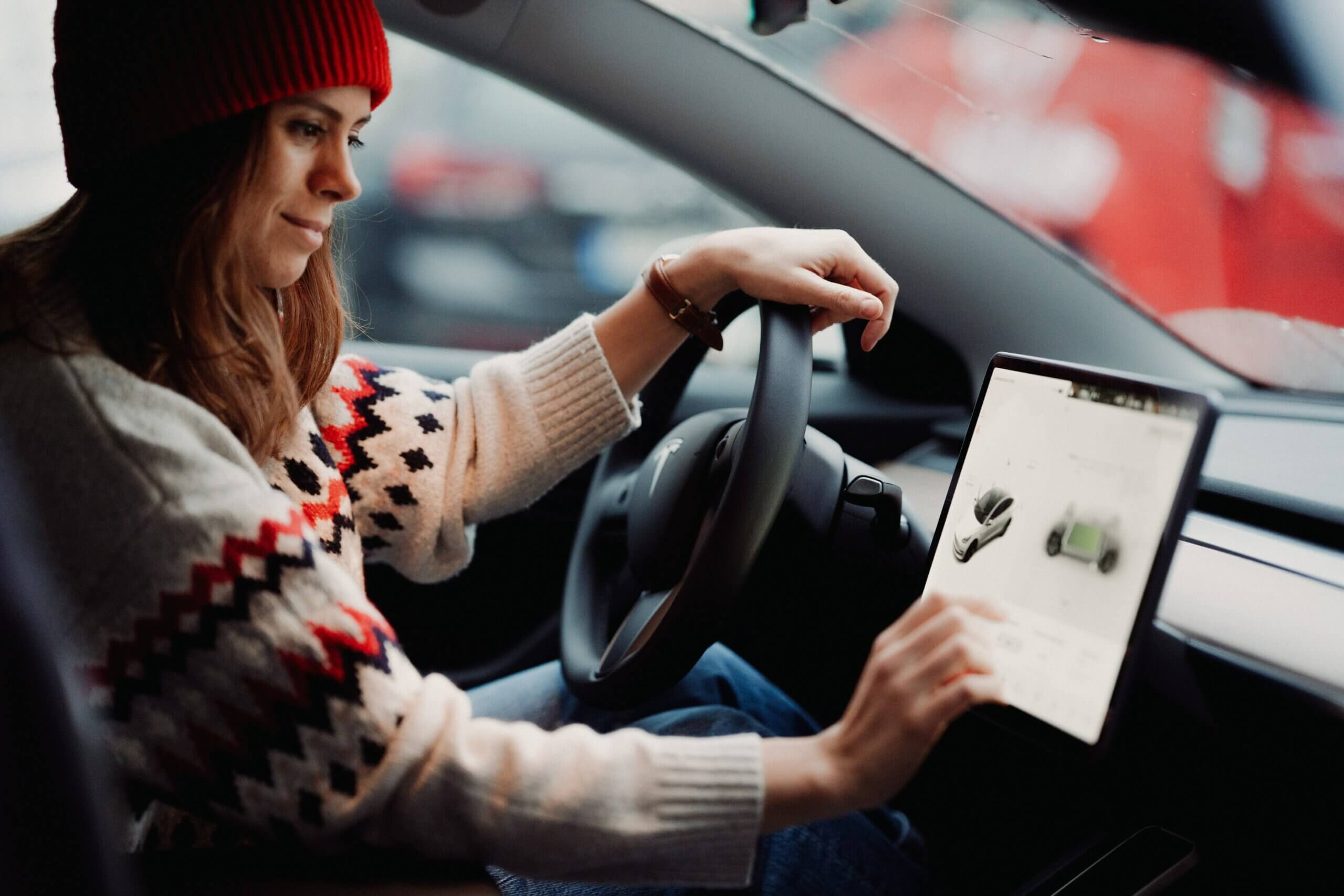 Frau sitzt in einem Tesla und bedient den Touchscreen.